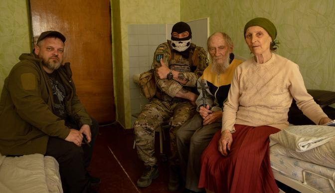Two older people with two men, one of whom is in military uniform.