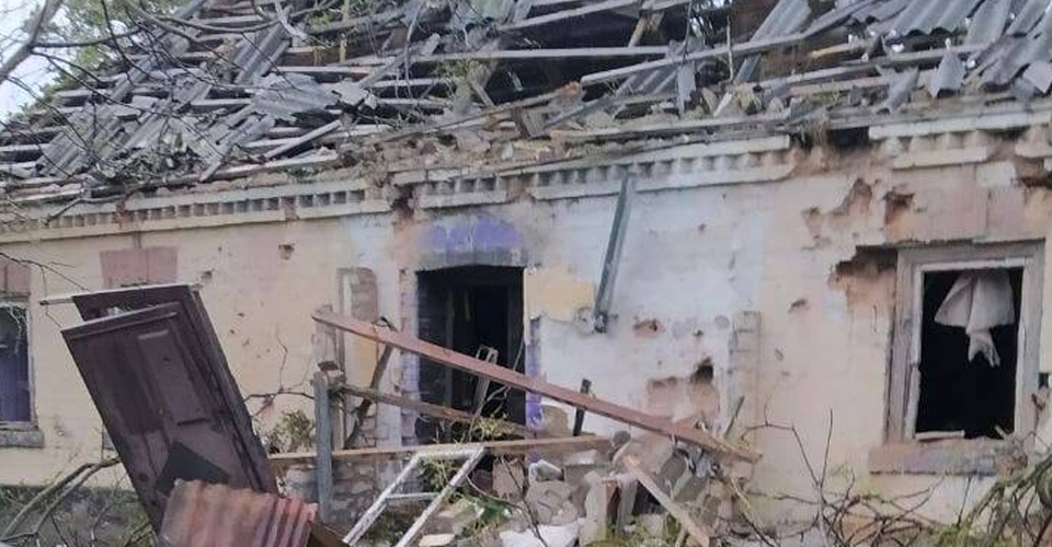 A damaged house with a collapsed roof and broken windows.